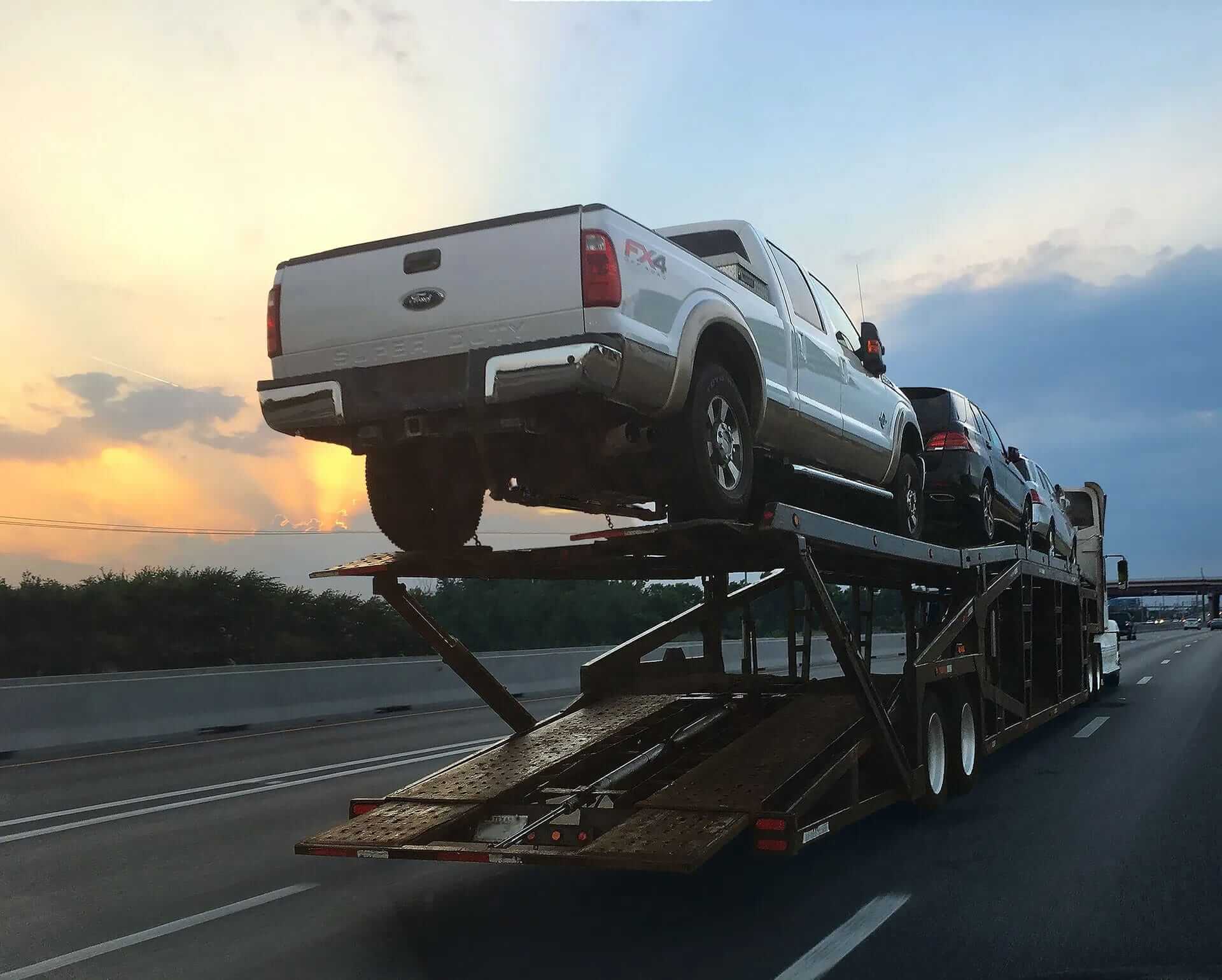 White Truck on Open Car Shipping Trailer During Sunset | National Transport Services