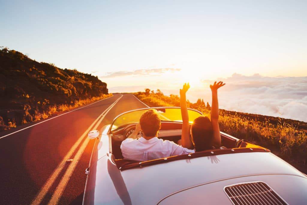 Couple driving along a cliff in a classic car