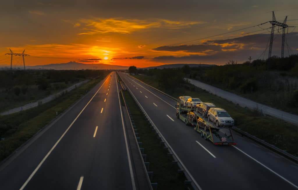 Open air car transport trailer on a highway