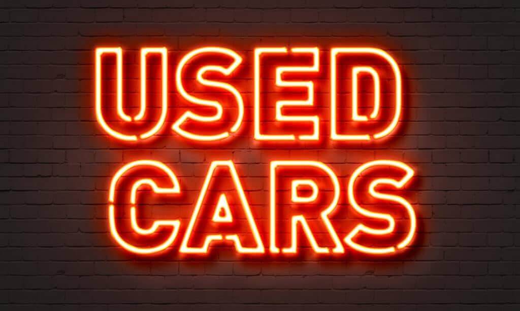 Used car websites the words used cars in neon orange lights with brick background