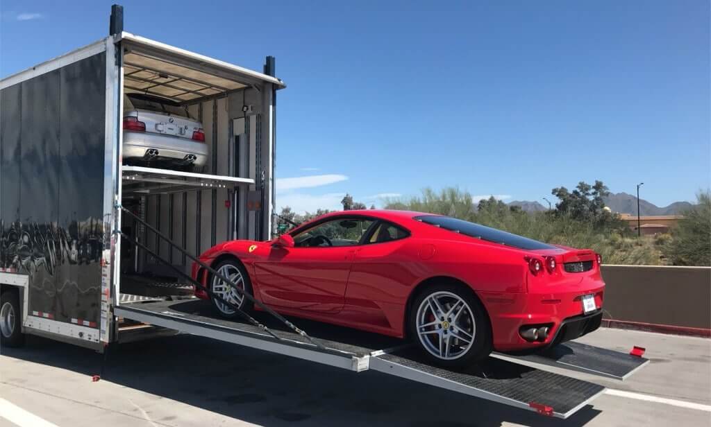 Red Ferrari 360 Coupe getting loaded into the back of an enclosed car trailer