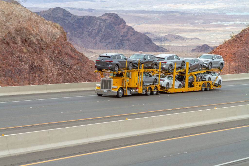 A yellow, fully loaded open trailer semi truck is driving on the highway—California to Texas auto transport. Need to ship a car? Get great customer service with our Texas car shipping services. Car shipping from California to Texas is done on a daily basis.