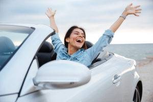 Woman in her convertible with hands in the air