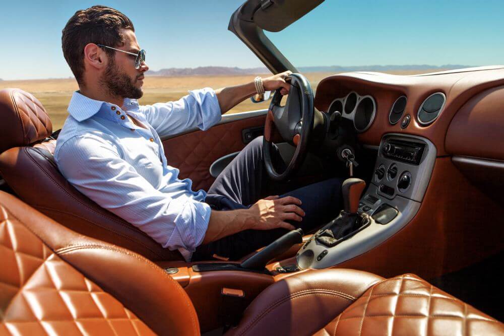 A man drives a luxury convertible.
