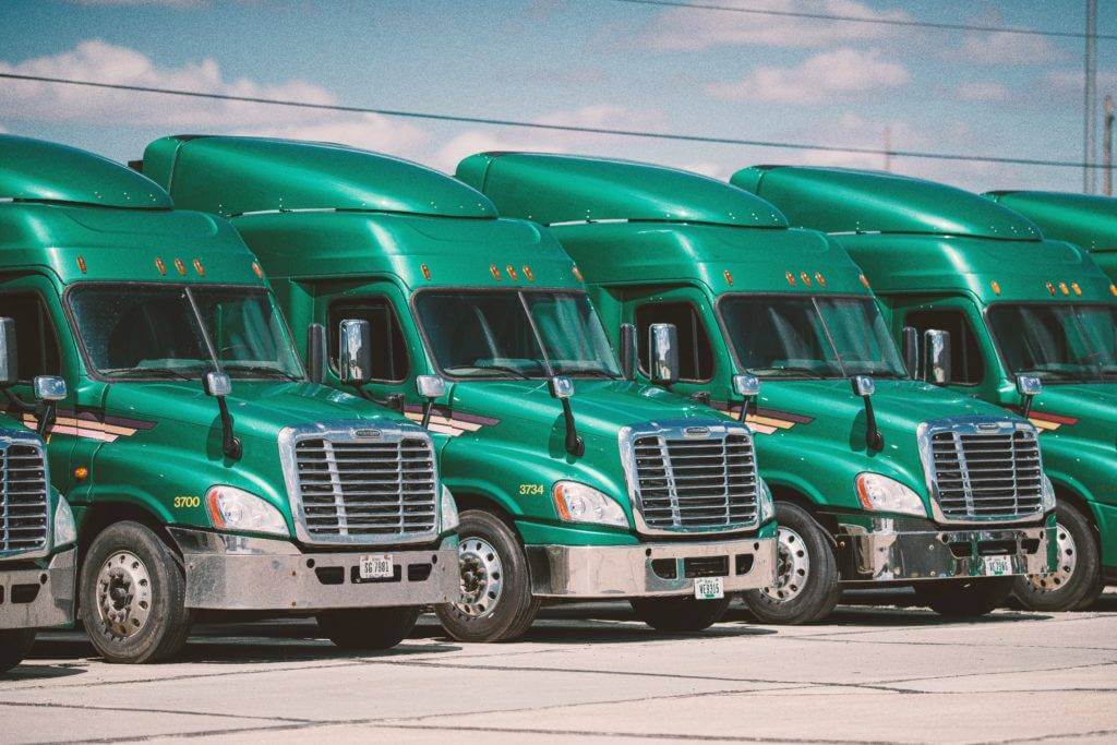 6 Green Semi Trucks are Parked. Car Shipping Services.