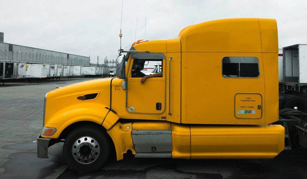 A yellow semi truck side view. How To Ship Car to Another State: Tips & Pricing (2023)
