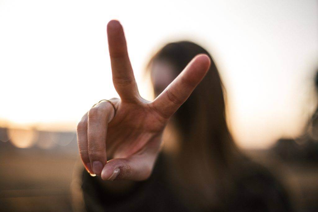 A woman holding up the peace sign with her hand. Auto transportation quote