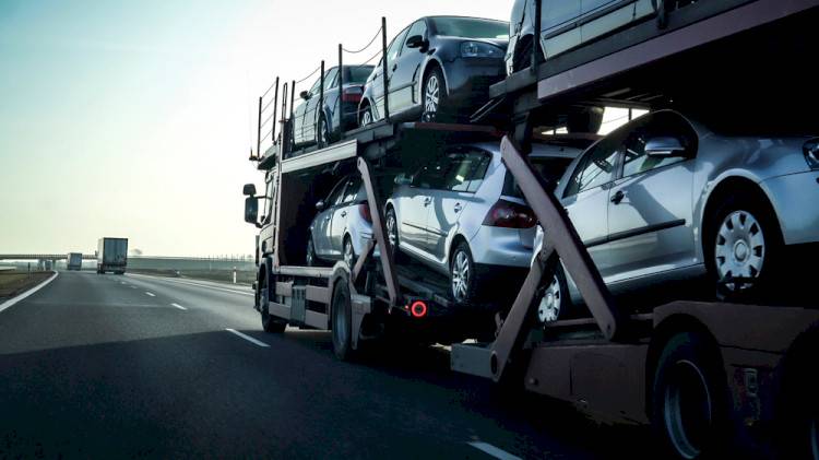 A car carrier transports vehicles down a road.