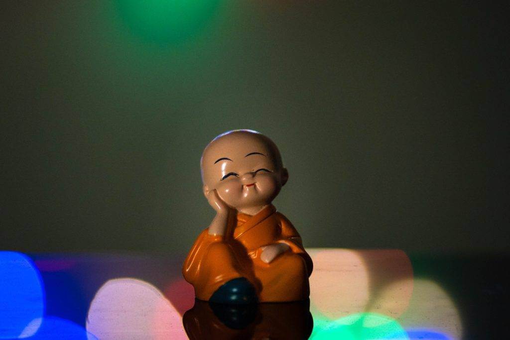 A toy Budda with one hand on his cheek and smiling. Get peace of mind when you ship in an enclosed auto transport trailer.