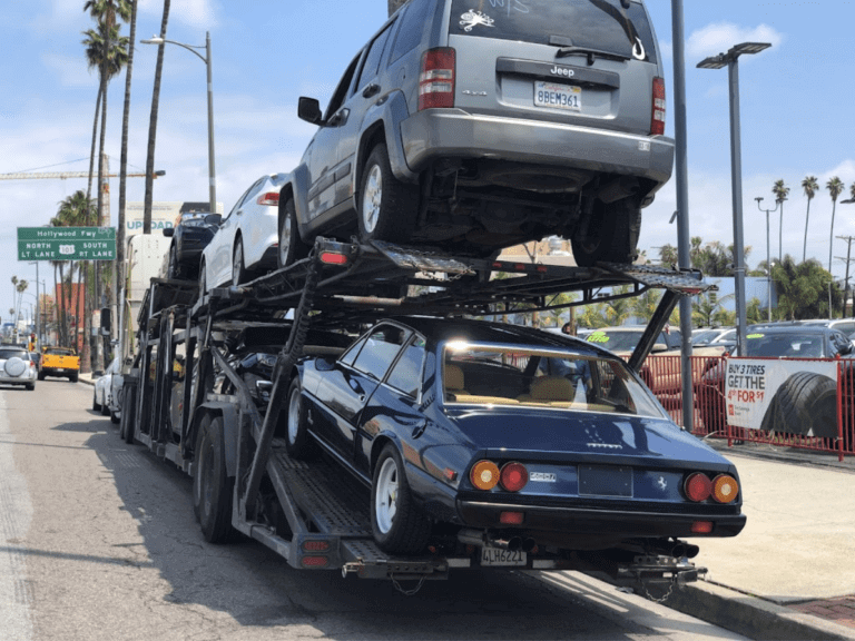 Open car transporter on Hollywood Blvd, loading a classic Ferrari 400i.