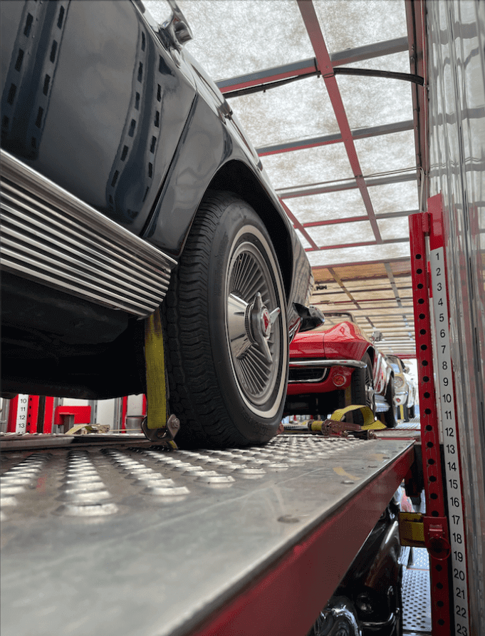 The view from inside an enclosed auto transport trailer where you can see two classic 1960s Chevrolet Corvettes.