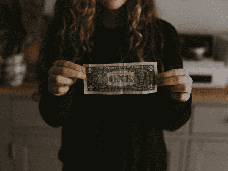 A woman in a black sweater is holding a single dollar bill on each side. We are a vehicle transport company.