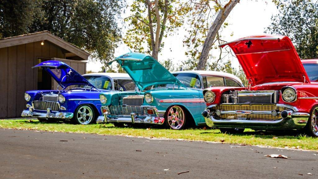 Three Chevrolet Bel-Air's parked on grass with the hoods open. NTS is the auto transport industry leader. Vehicle transport Company.
