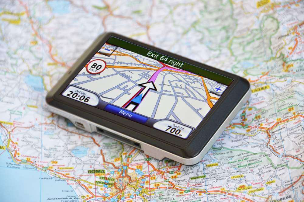 A satellite navigation system sits on a map. Plan on moving a car across the country? Classic car or a new car, we are the experts in shipping cars.