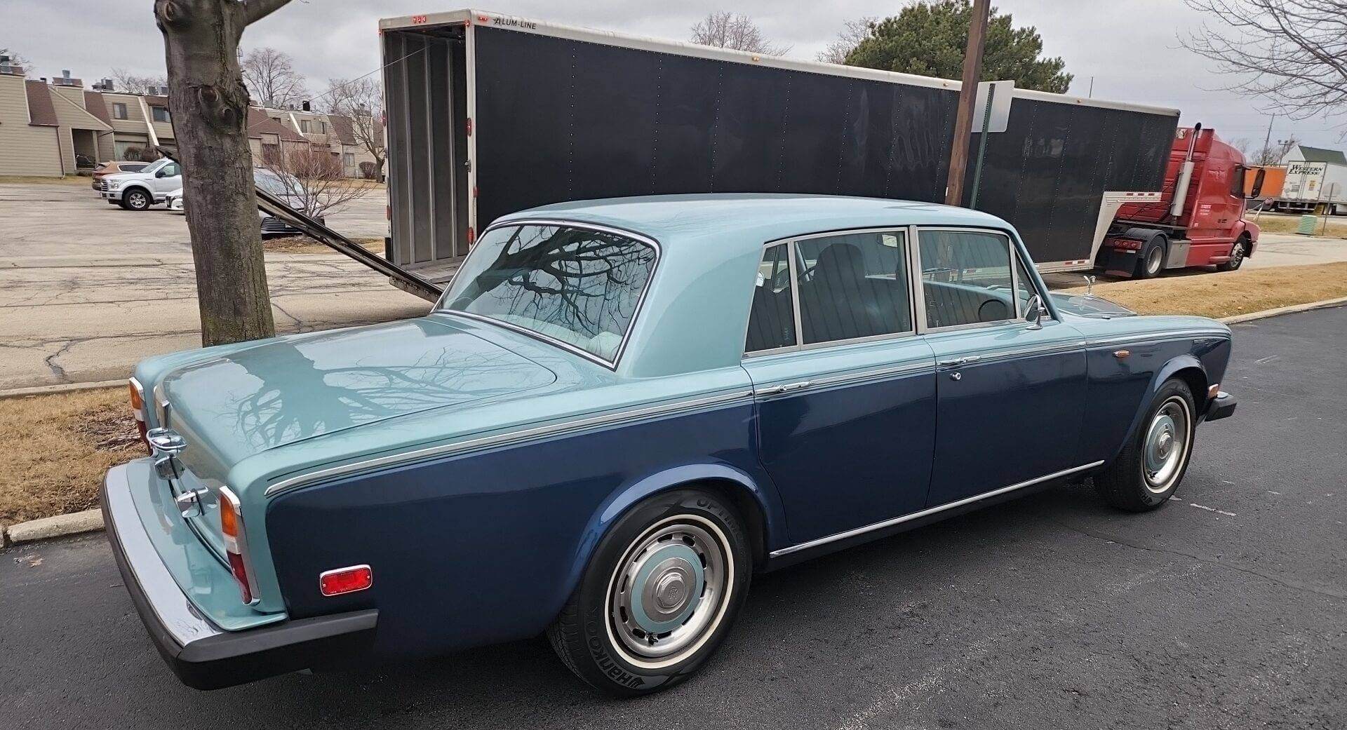 A classic Rolls Royce with an enclosed auto transport trailer behind it. Getting cars shipped is a pretty straight forward service.