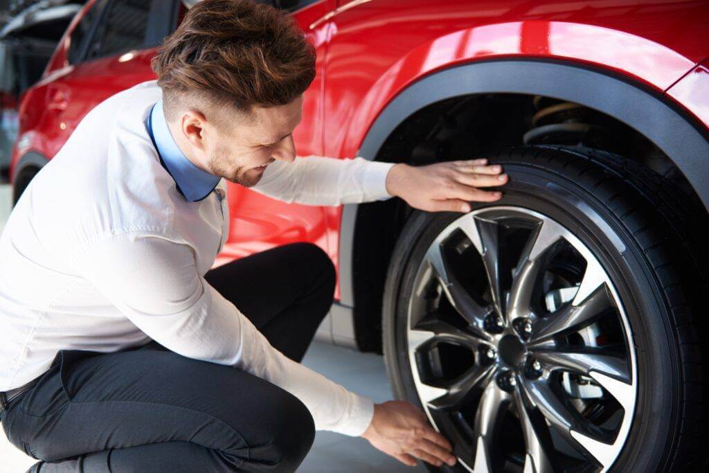 A man is checking the wheels for damage.