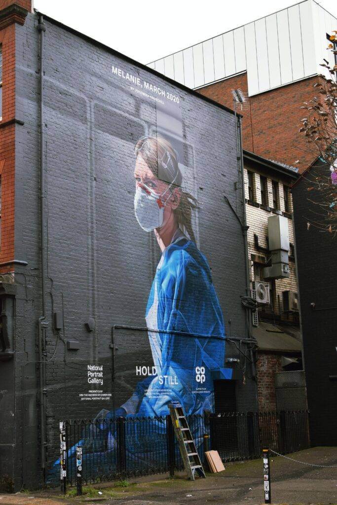 A large painted mural on the side of a building of a nurse in her scrubs. Car shipping for traveling nurses is a necessity for the Medical industry.