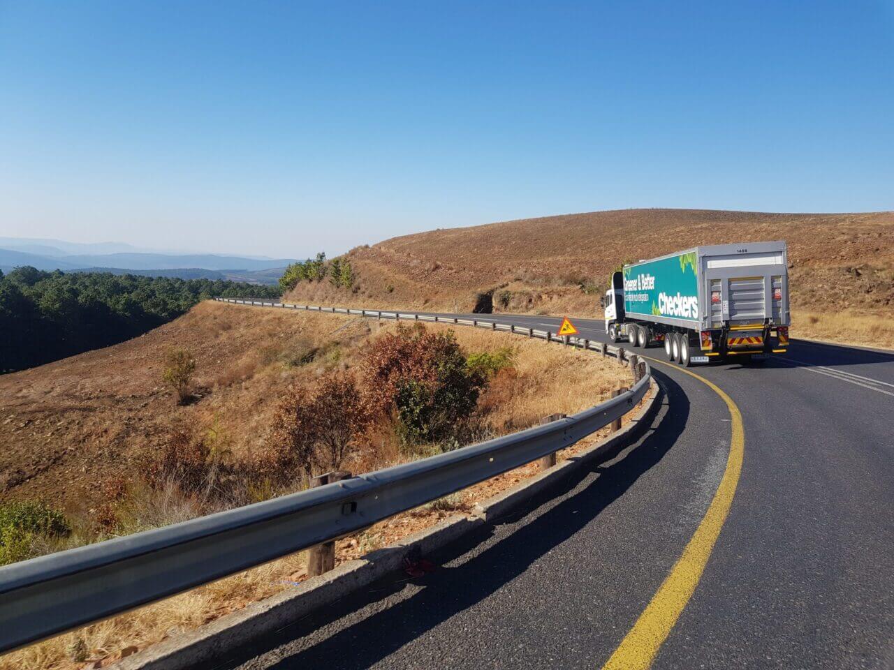 A semi-truck driving away on a curving highway. National Transport Services is the leader in auto transport companies. Find out the average car shipping costs with free car shipping rates.