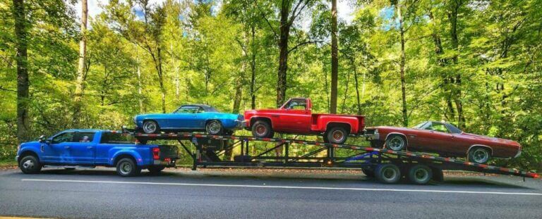 Dually Pickup Truck with a three-car wedge trailer hauling three classic vehicles. Shipping cost for a car can vary based on your unique needs.