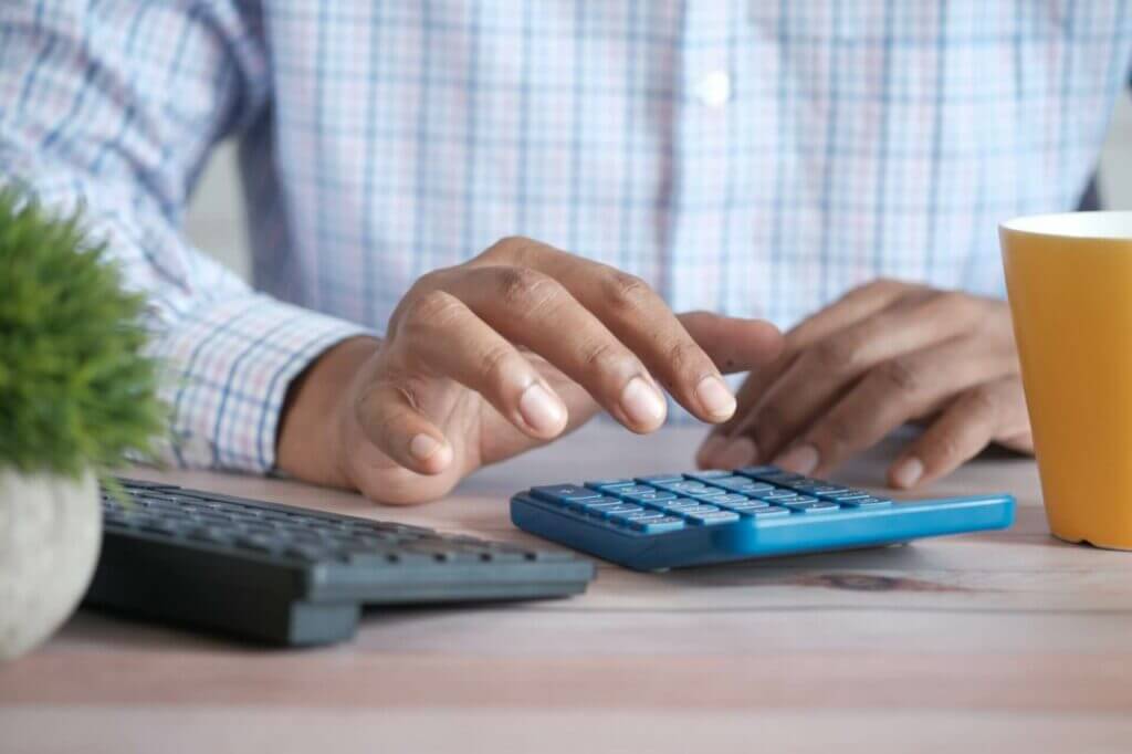 A man is typing on a calculator.